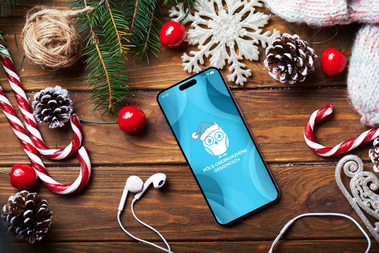 Gemeinde24 App auf einem Smartphone, dass auf einem weihnachtlich gedecktem Tisch liegt.